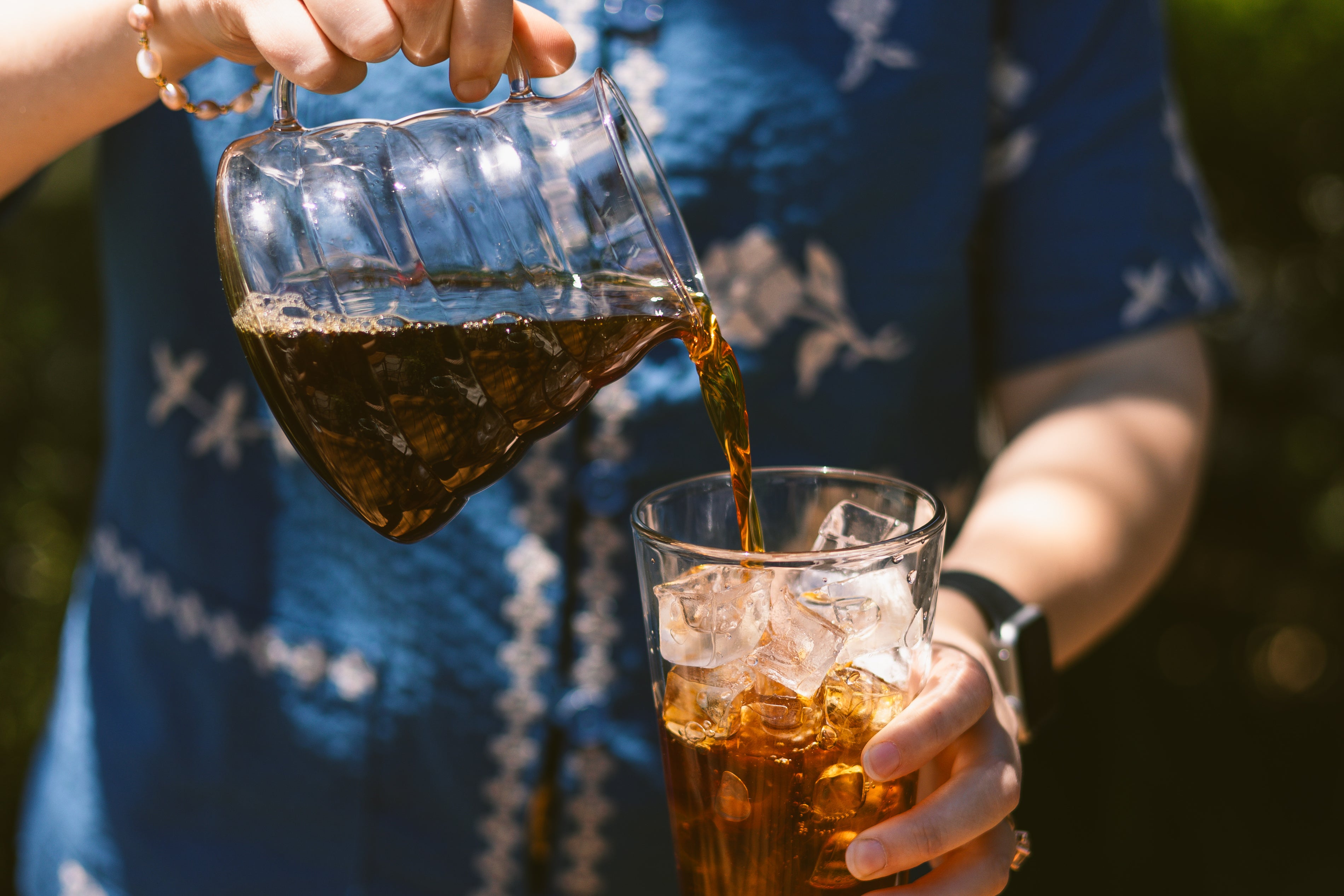 Person pouring coffee from ranger server into a pint glass filled with ice.