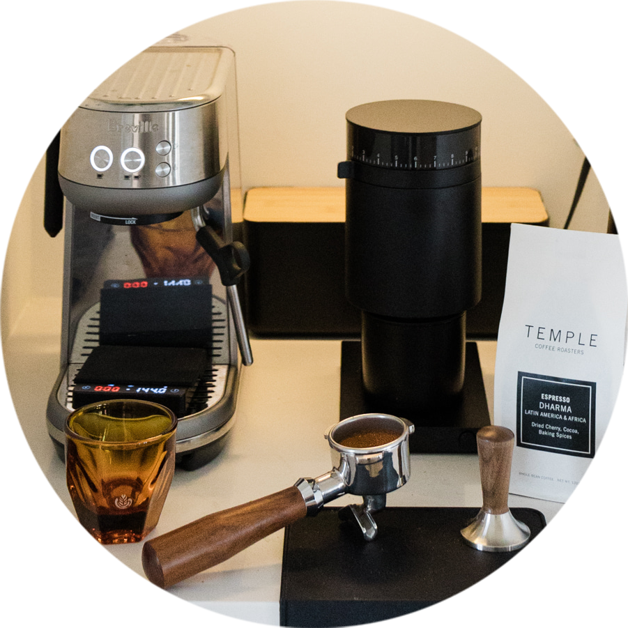 Coffee-making equipment including a coffee machine, grinder, and espresso tool on a counter.