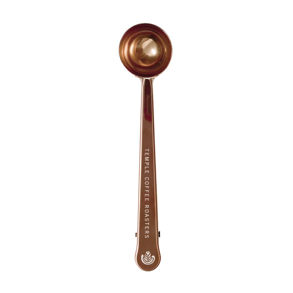 Bronze coffee scoop with 'Temple Coffee Roasters' branding on a white background