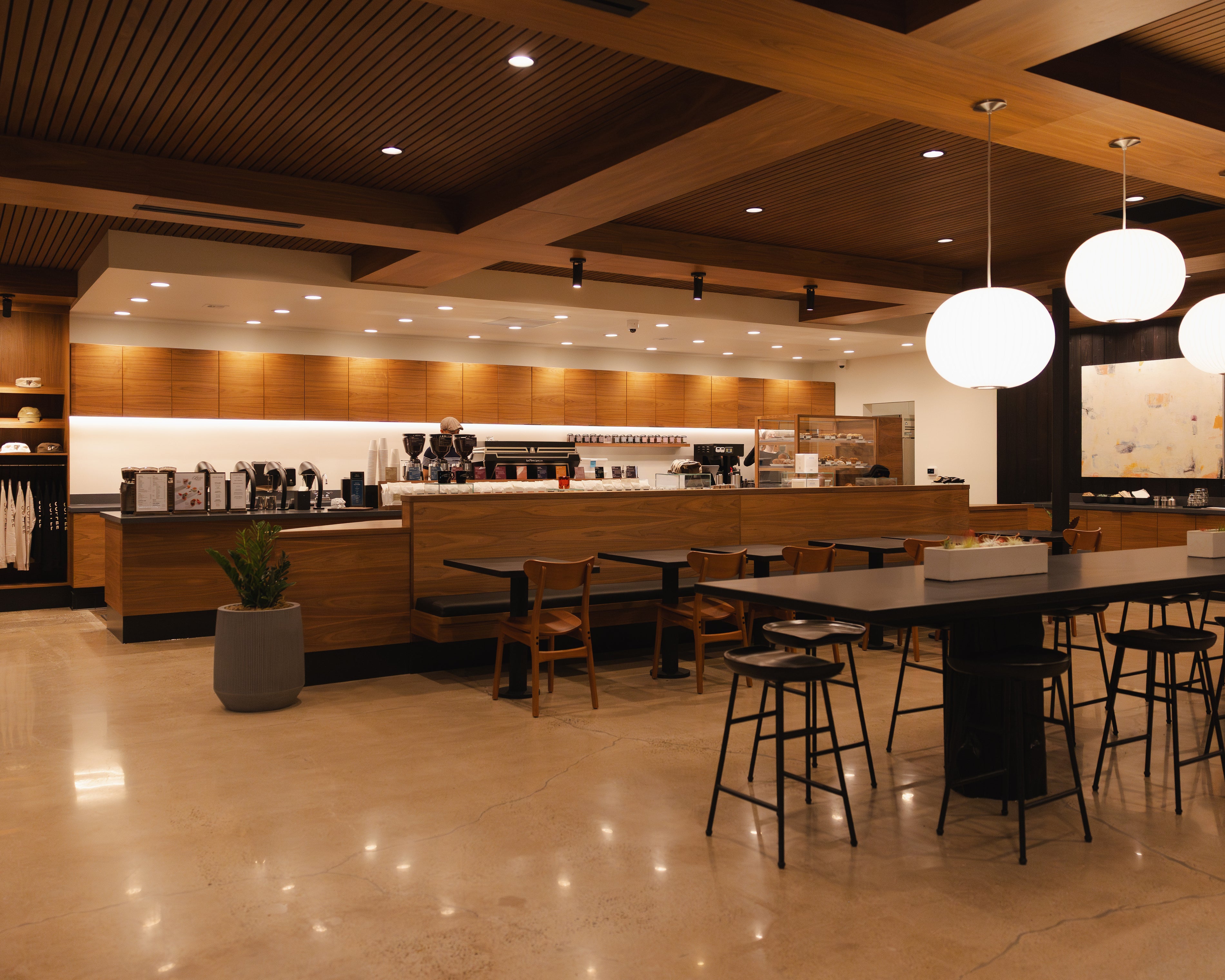 Modern coffee shop interior with wooden counters, chairs, and tables.