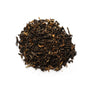 A pile of dry black tea leaves with some golden tips, on a white background.